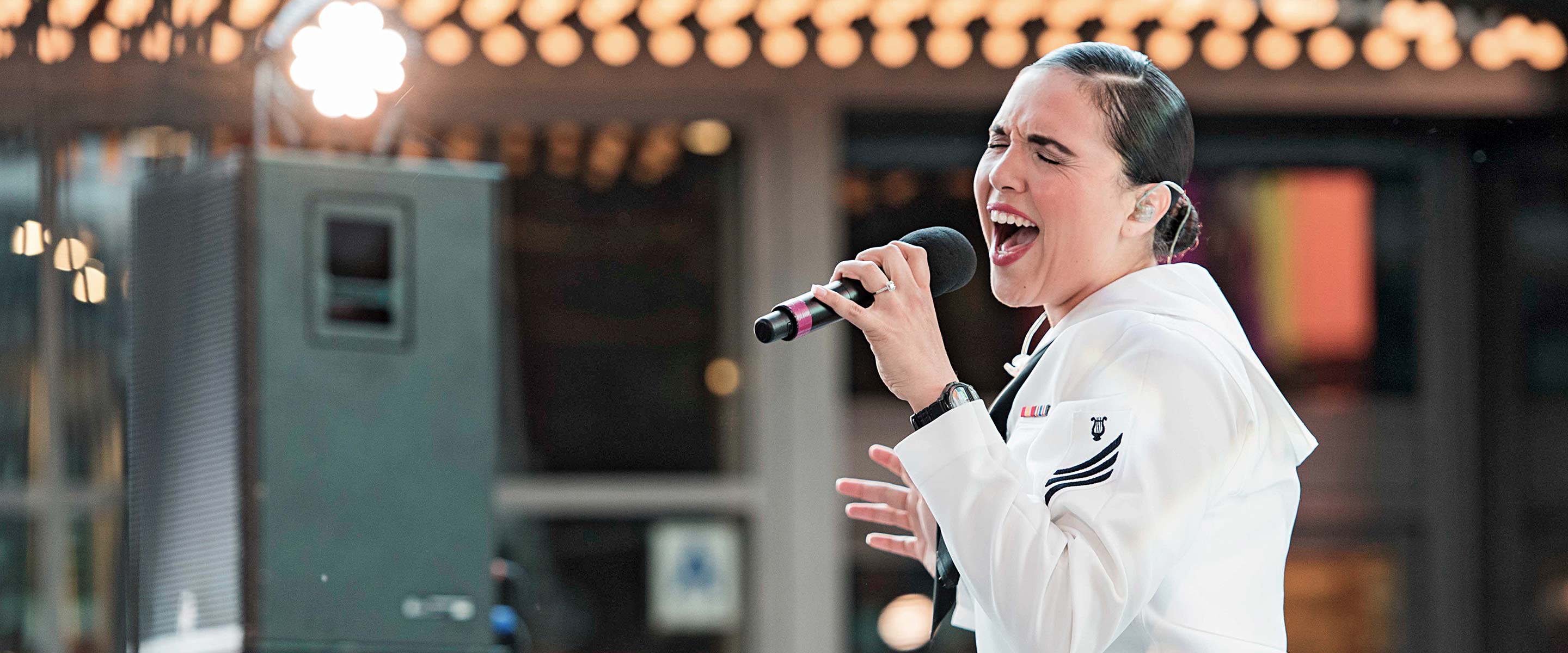 Navy musician in uniform sings into a microphone