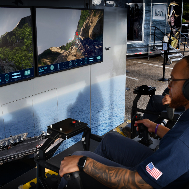 Man tries fighter jet simulator at The Strike Group experience, presented by America's Navy.