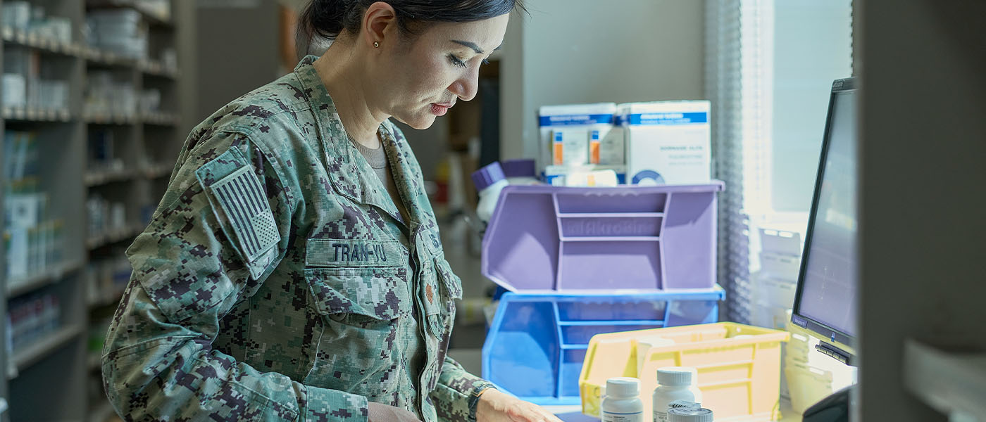 Navy pharmacist carefully counting pills in a pharmacy, ensuring accurate medication dispensing.