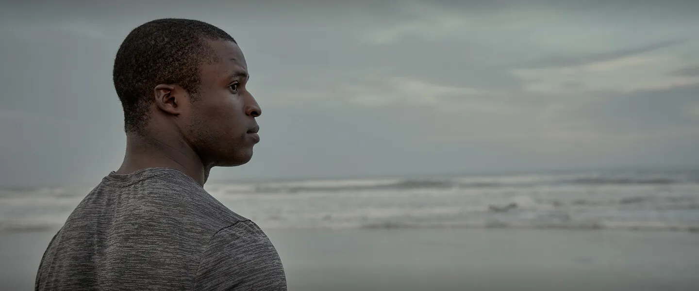 A U.S. Navy Reserve Sailor Jesse Iwuji looks out at the ocean on a beach in San Diego, CA