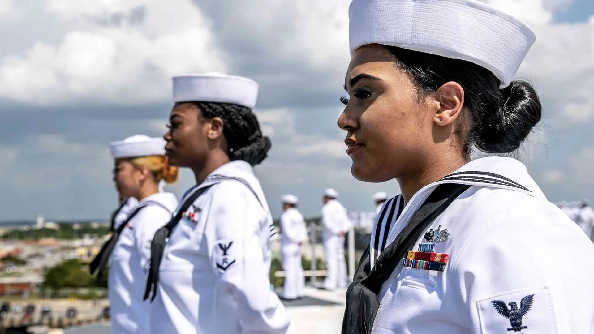 A U.S. Navy Sailor is manning the rails aboard an aircraft carrier.